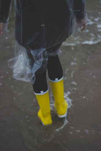 person wearing clear plastic raincoat and pair of yellow rainboots